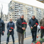 O Alto Comissário do ACNUR, Filippo Grandi (ao centro da foto), ao lado de representantes das autoridades locais, deposita flores em um prédio residencial que foi destruído durante um ataque com mísseis em 14 de janeiro de 2023, na cidade de Dnipro, Ucrânia. (© ACNUR/Colin Delfosse)