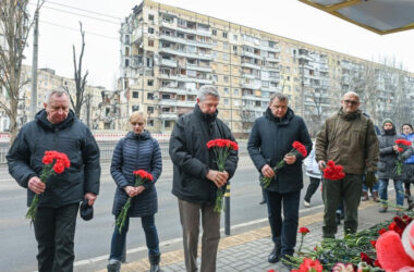 O Alto Comissário do ACNUR, Filippo Grandi (ao centro da foto), ao lado de representantes das autoridades locais, deposita flores em um prédio residencial que foi destruído durante um ataque com mísseis em 14 de janeiro de 2023, na cidade de Dnipro, Ucrânia. (© ACNUR/Colin Delfosse)