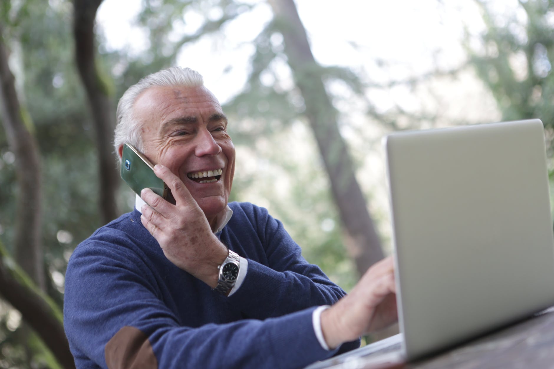 man in blue long sleeve sweater using cellphone