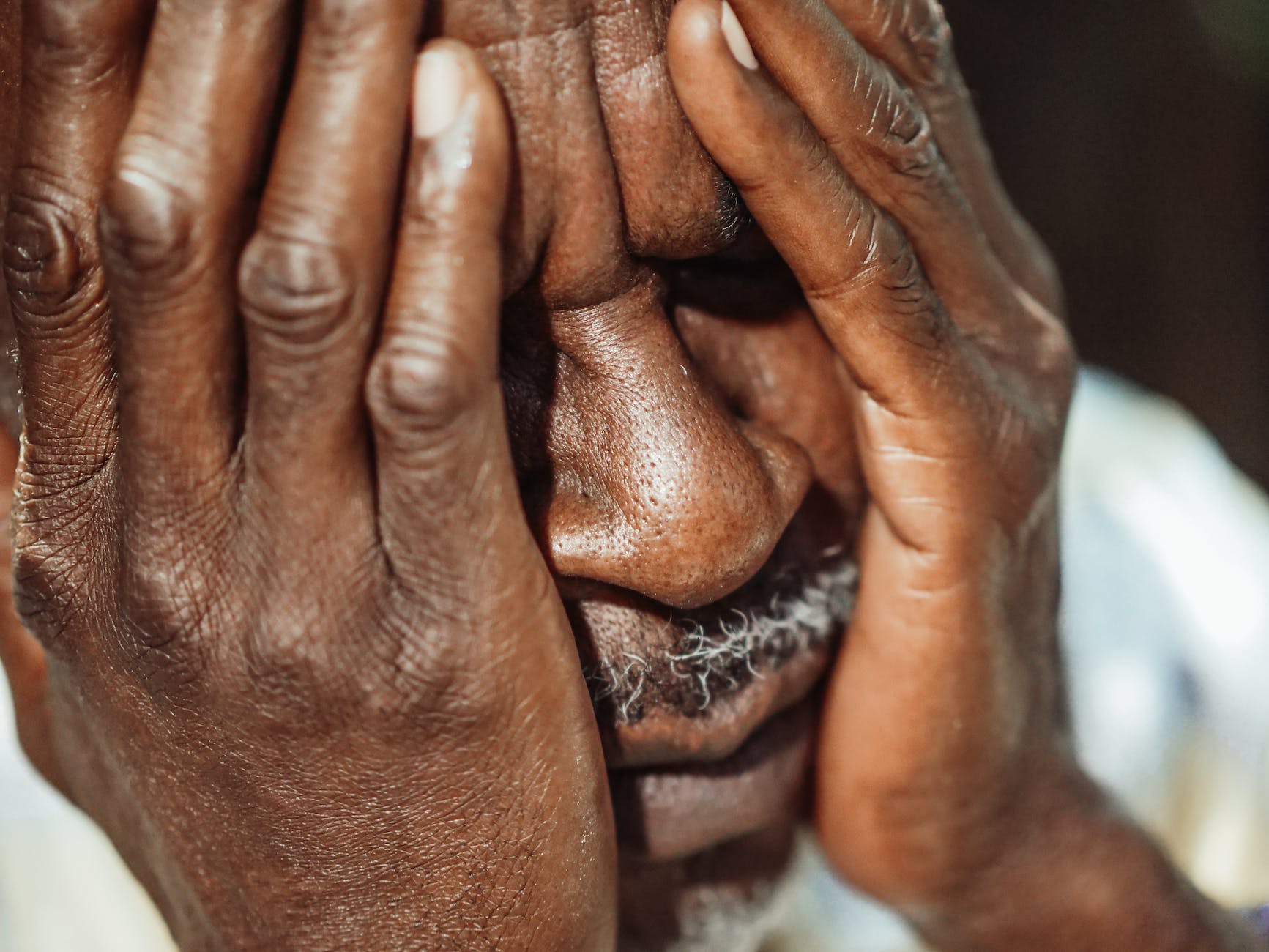 man in white shirt covering his face