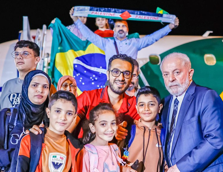 Mohammed (de vermelho) posa com o presidente Lula ao lado da família repatriada no voo com o grupo de Gaza. Foto: Ricardo Stuckert / PR