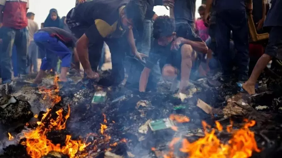 Palestinos procuram por comida entre escombros queimados após ataque israelense em Rafah – Foto: Mohammed Salem