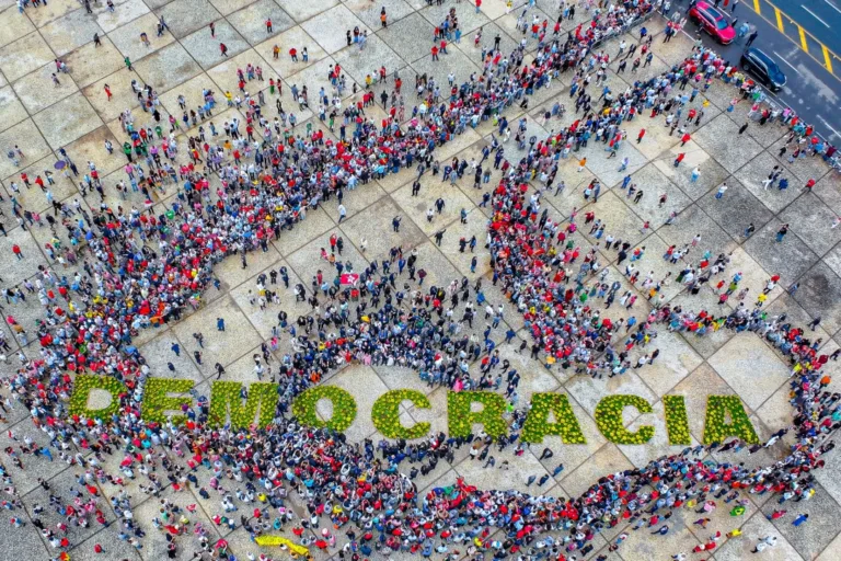 DEMOCRACIA – Após a solenidade, o presidente desceu a rampa do Palácio do Planalto com autoridades para se juntar ao público que estava na Praça dos Três Poderes para o Abraço da Democracia. Eles se posicionaram ao lado de uma estrutura composta por centenas de vasos de flores que formavam a palavra democracia. CONSCIÊNCIA - Vinda de Goiânia, a professora e funcionária pública Marta Luíza viajou com o esposo, Junior Rabelo, para a celebração. Ela destacou a difícil recuperação do país após os episódios de invasão e vandalismo. “A recuperação física já é todo um trabalho, um esforço consciente em torno do que representam esses símbolos na Praça dos Três Poderes, mas a recuperação política e social é ainda mais difícil e lenta”, disse Marta.