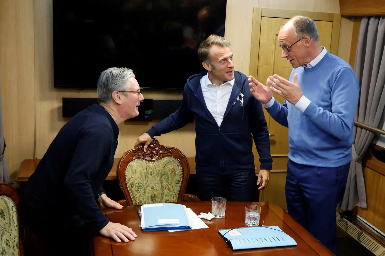 O primeiro-ministro britânico, Keir Starmer, e o presidente francês, Emmanuel Macron, ouvem o chanceler alemão, Friedrich Merz, num trem para Kiev em 9 de maio de 2025