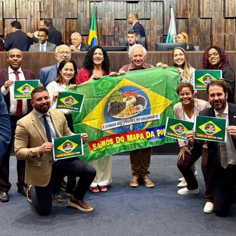 Deputados de oposição exibem bandeira na Alerj para celebrar a saída do Brasil do mapa da fome. Parlamentares bolsonaristas reagem com ironias durante sessão.