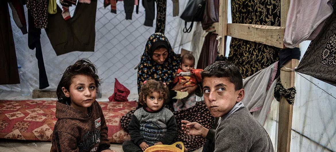Unicef/Abed Zagout Uma família é vista sentada ao redor de uma tigela de feijão em sua tenda em Rafah, no sul da Faixa de Gaza.