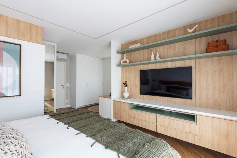 A parede em frente à cama pode seguir diversas linhas decorativas, recebendo pinturas, revestimentos ou painéis de marcenaria. O cuidado está em combinar o material e não competir com a TV | Projeto: Mari Milani | Foto: Mariana Camargo A parede em frente à cama pode seguir diversas linhas decorativas, recebendo pinturas, revestimentos ou painéis de marcenaria. O cuidado está em combinar o material e não competir com a TV | Projeto: Mari Milani | Foto: Mariana Camargo