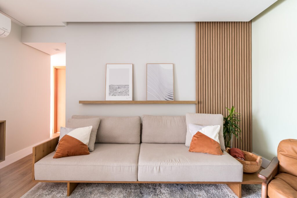 De acordo com a arquiteta Cinthia Claro, há casos em que o objetivo das prateleiras é apenas preencher uma parede vazia e complementar a decoração, tal qual ela realizou nesta sala de estar. Posicionada um pouco acima do sofá, ela cumpre a função de apoiar os quadros | Foto: Erika Waldmann